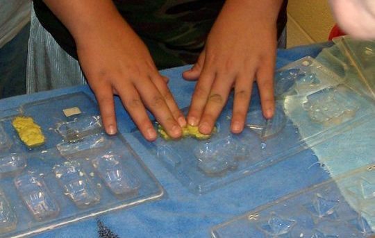 SWMD Bonnie Classroom Pics 013b, kid putting paper mache in plastic molds