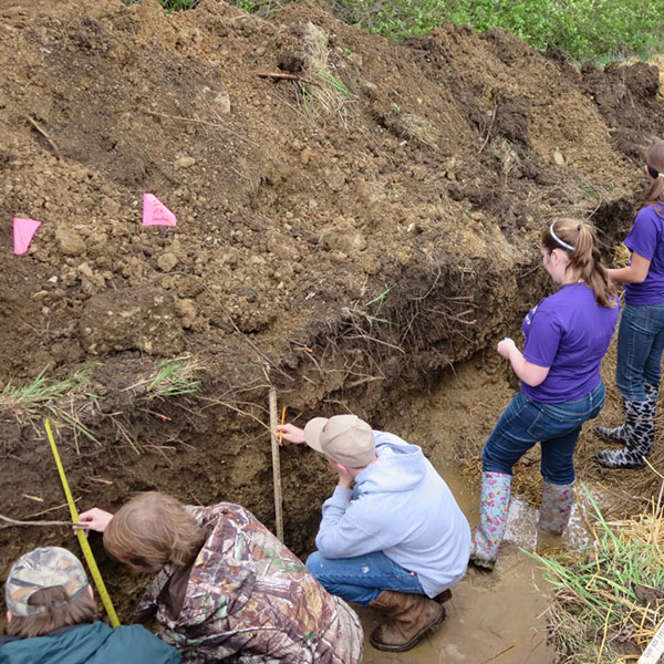 Soil and Water Conservation, people in a ditch meassuring ground errosion